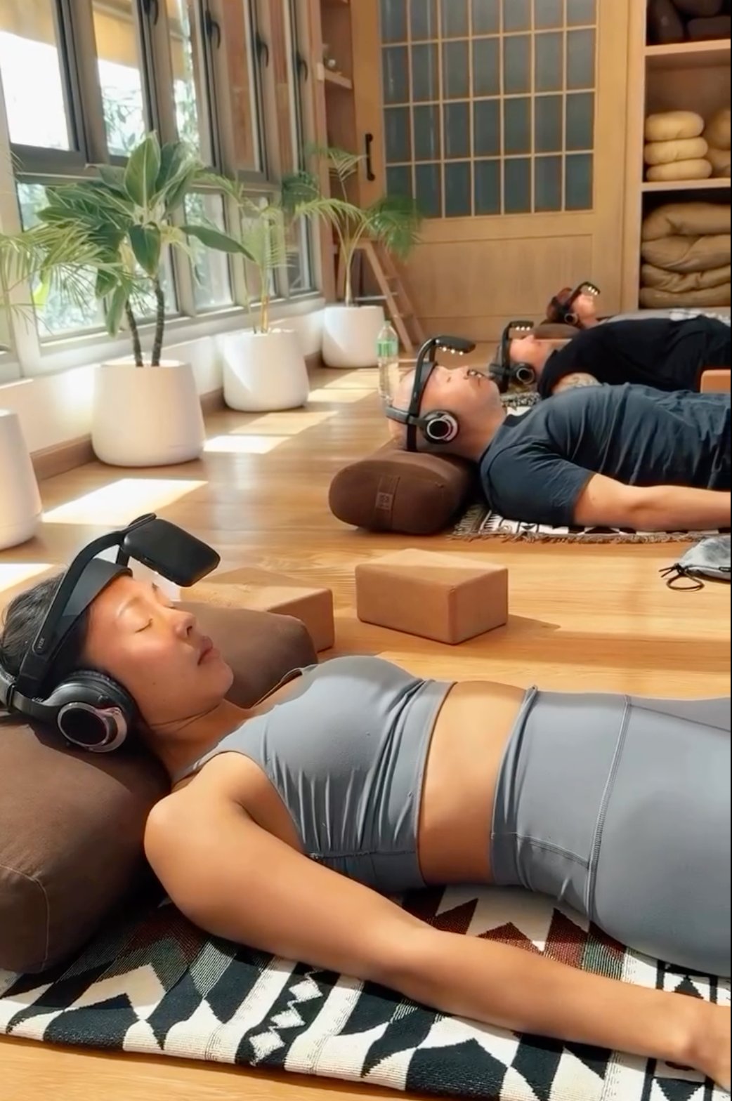 Group session with multiple people lying down using NeuroVizr together in a bright wellness studio